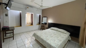A bedroom with a bed, a desk, a chair, a ceiling fan, and a window with curtains. - Hotel Moreno (Ciudad Valles)