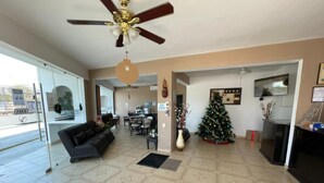 A spacious living room with a ceiling fan, a Christmas tree, and a fireplace. - Hotel Moreno (Ciudad Valles)