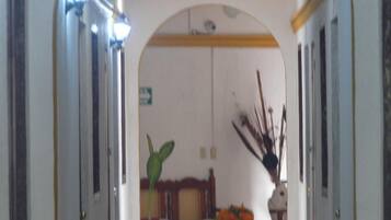 Um corredor com um banco, uma planta e um vaso com flores.