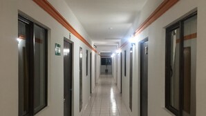 A long, narrow hallway with doors on both sides, tiled floors, and overhead lighting. - Hotel Moreno (Ciudad Valles)