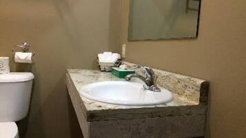 Ein Badezimmer mit einem weißen Waschbecken, einem Spiegel und einer Toilette.