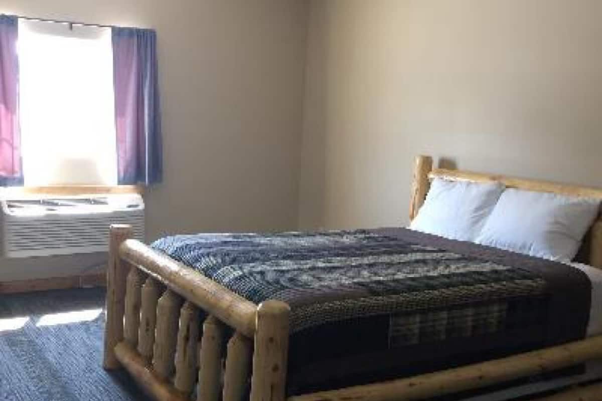 A room with a wooden bed, a window with curtains, and a radiator.
