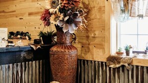 Un intérieur rustique avec un mur en bois, un vase décoratif rempli de fleurs et une figurine de cheval sculptée dans le bois.