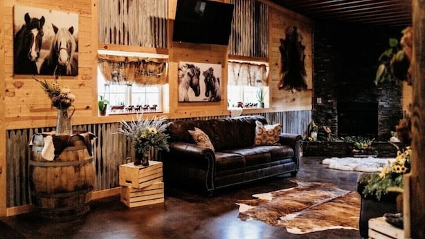 Un intérieur rustique avec des murs en bois, un canapé en cuir et des têtes d’animaux décoratives accrochées au mur.
