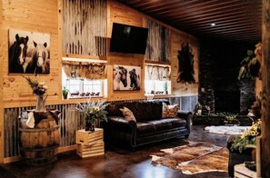A rustic interior with wooden walls, a leather sofa, and mounted animal headpieces. - Big Horse Inn and Suites (Lewistown)