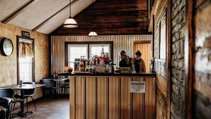 Un café chaleureux avec des éléments décoratifs en bois, un bar et un espace salon avec des tables et des chaises.