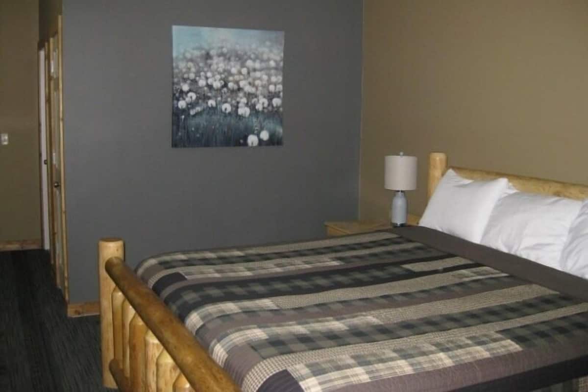 A bedroom with a bed, a nightstand, a lamp, and a painting of flowers on the wall.