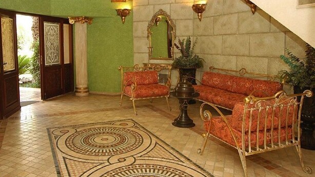 Un amplio pasillo con muebles ornamentados, un espejo grande y una alfombra estampada.