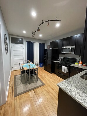 A compact kitchen with dark cabinets, a microwave, a stove, and a dining area with a table and chairs.