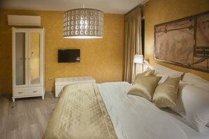 Una habitación de hotel con cama, armario, televisor y un cuadro en la pared.