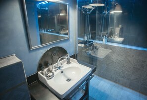 Un baño moderno con un espejo grande, un lavamanos y una ducha.