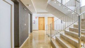 A modern hotel corridor with a staircase, wooden doors, and a fire extinguisher.