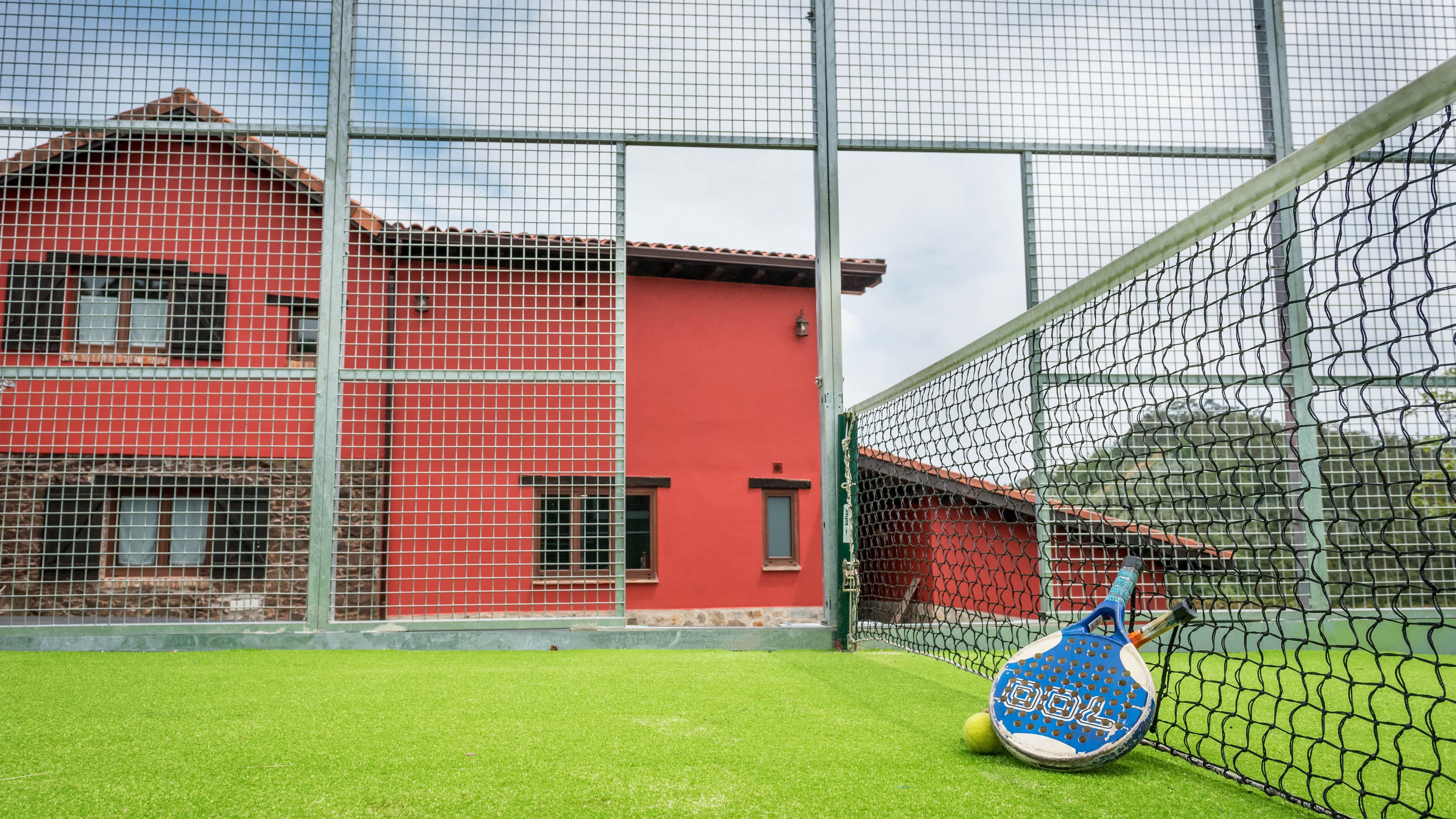 A tennis court with a net, a tennis racket, and a ball.