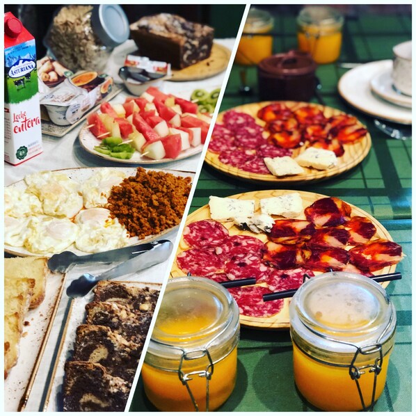 Une table sur laquelle on trouve divers aliments, notamment une assiette de charcuterie, une assiette de fruits et deux pots de jus d’orange.