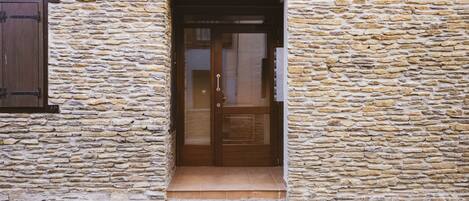 Un edificio de piedra con una puerta de madera y una ventana con persiana.