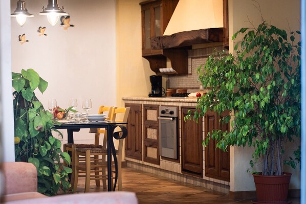 A cozy kitchen with wooden cabinets, a dining table set for four, and a large potted plant.