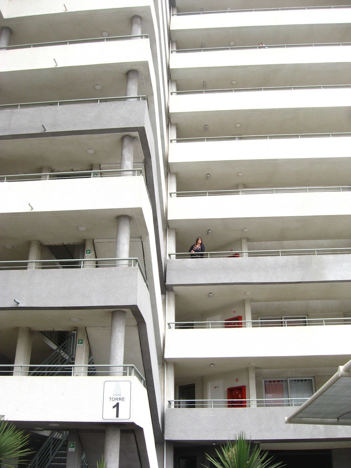 A multi-story building with balconies and a sign indicating the building number.