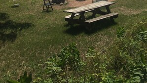 A lakeside picnic area with a wooden picnic table and several chairs. - Monthly Lakeside Retreat Cabin (Danbury)
