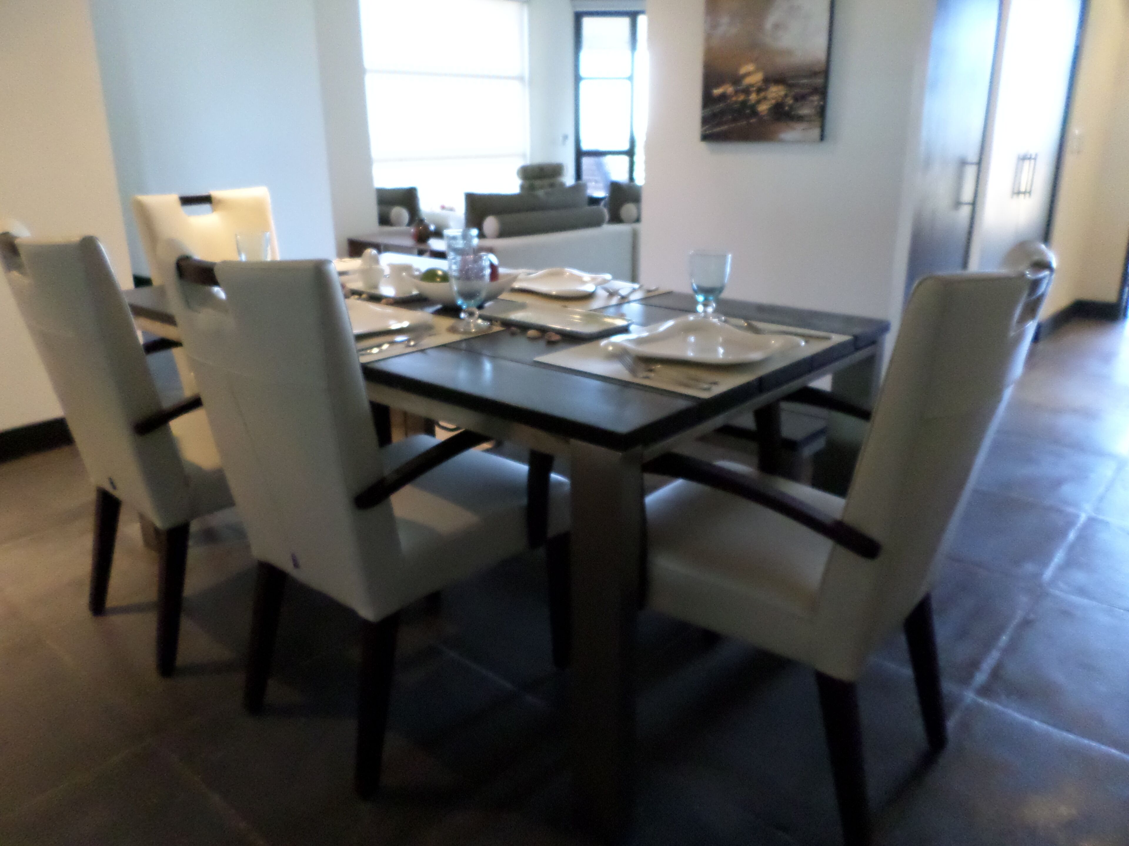 A dining area with a rectangular table set for four, surrounded by four chairs.