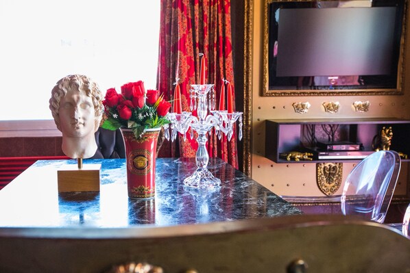 A marble table with a bust, a vase of red roses, and a candle holder.
