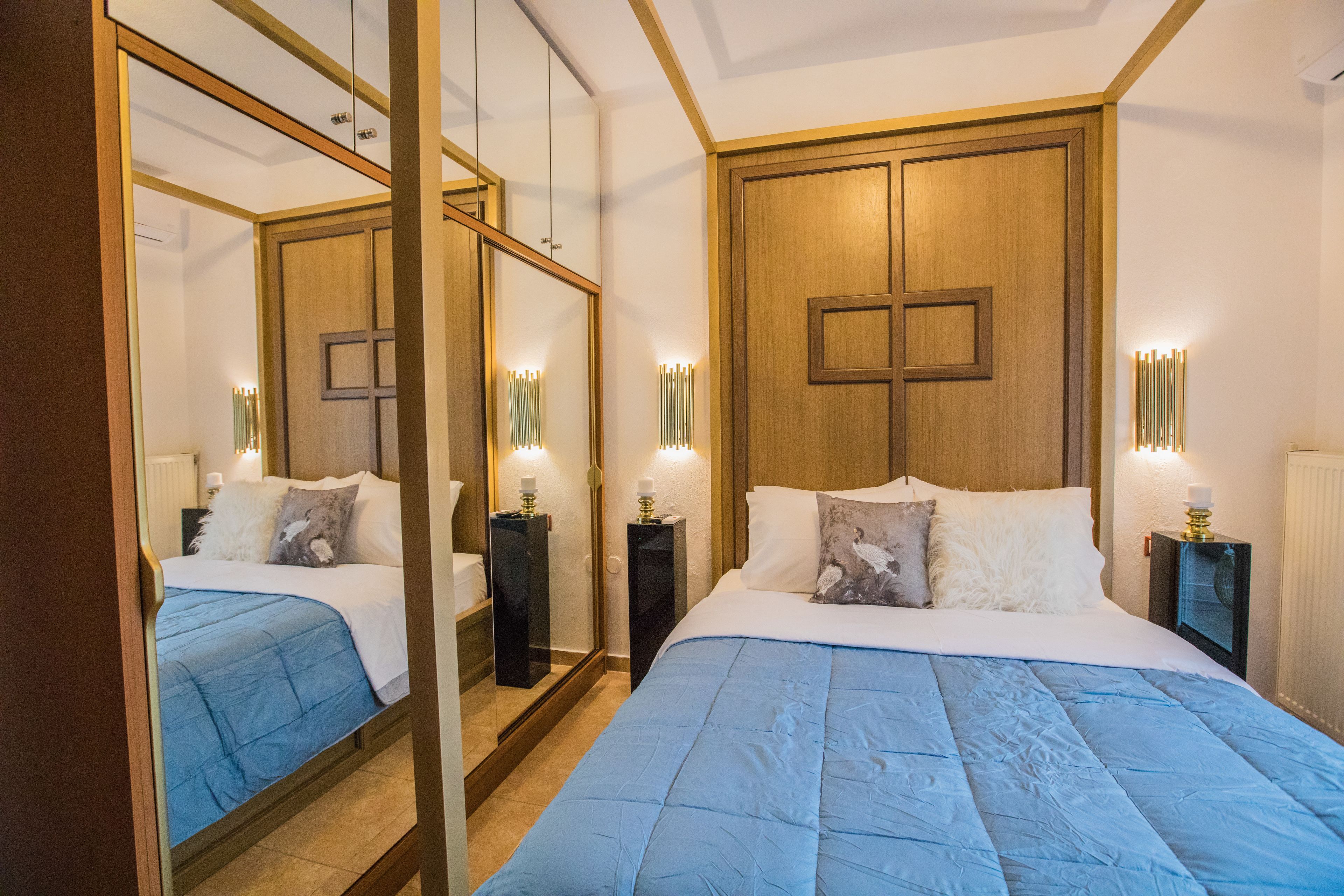 A hotel room with a large bed, a wooden wardrobe, a mirror, and bedside lamps.