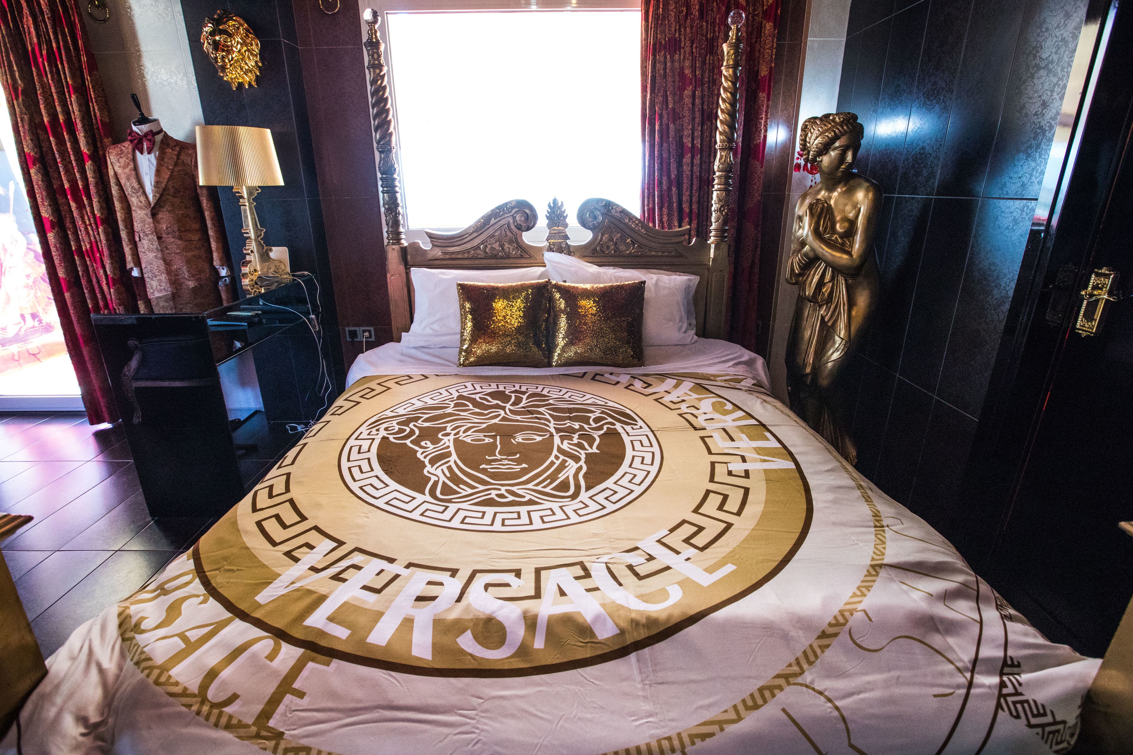 Ein luxuriöses Schlafzimmer mit einem großen Bett, einer Statue und einer in einem Anzug gekleideten Mannequin.