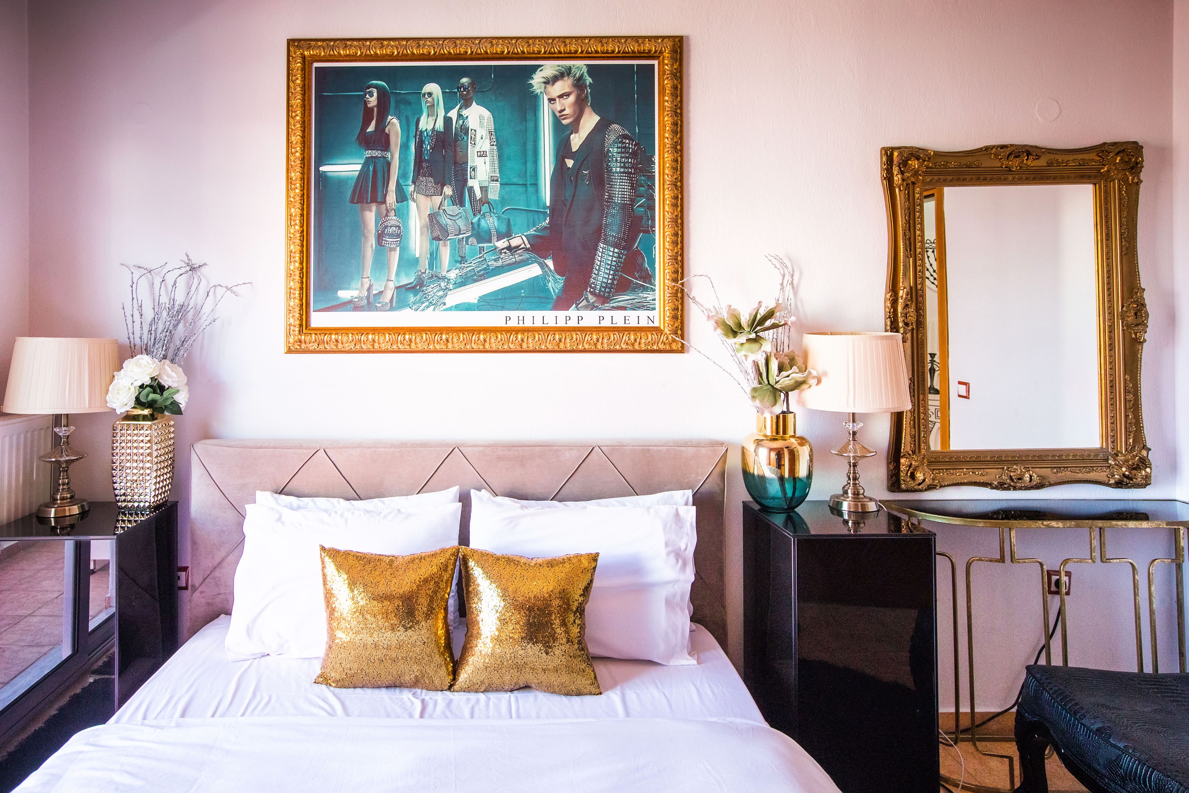 A hotel room with a large bed, two bedside tables, a mirror, and a framed poster on the wall.