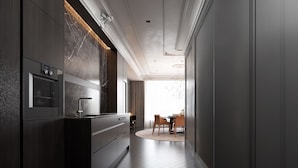 A modern kitchen with dark wood cabinetry, a marble backsplash, and a built-in oven. - Luxury Suites (Drama)