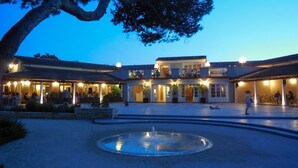 A hotel courtyard with a central fountain, outdoor seating areas, and a building with multiple balconies.