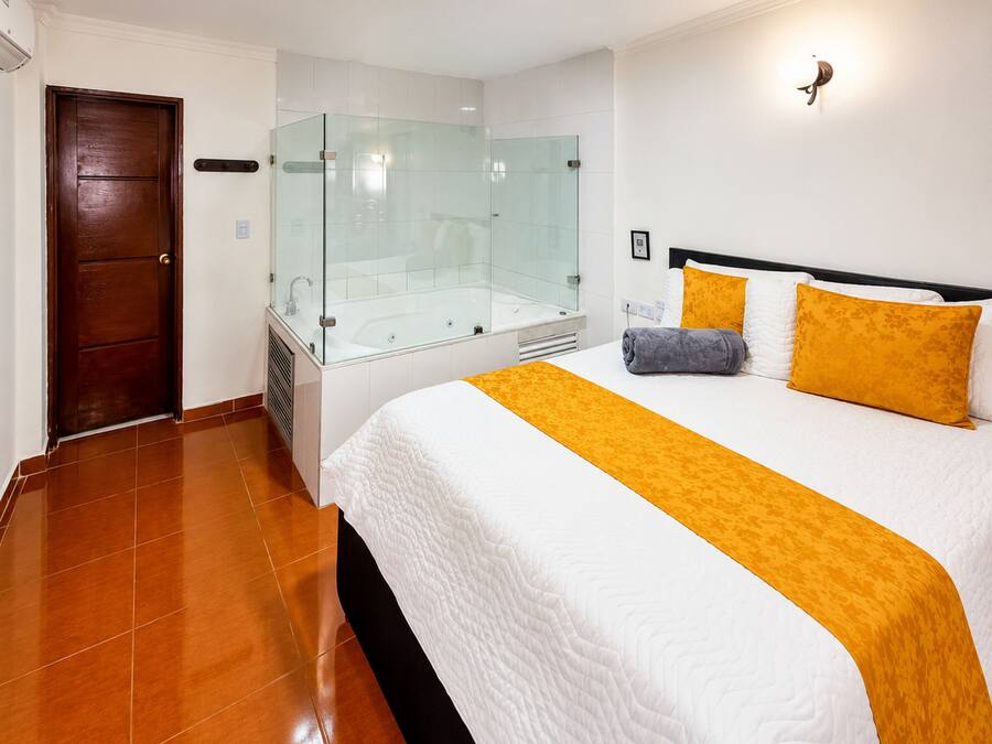 Ein Hotelzimmer mit einem großen Bett, einer gläsernen Dusche und einer Holztür.