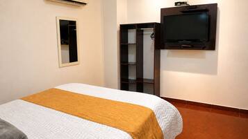 Una habitación de hotel con una cama, un televisor montado en la pared y un armario.