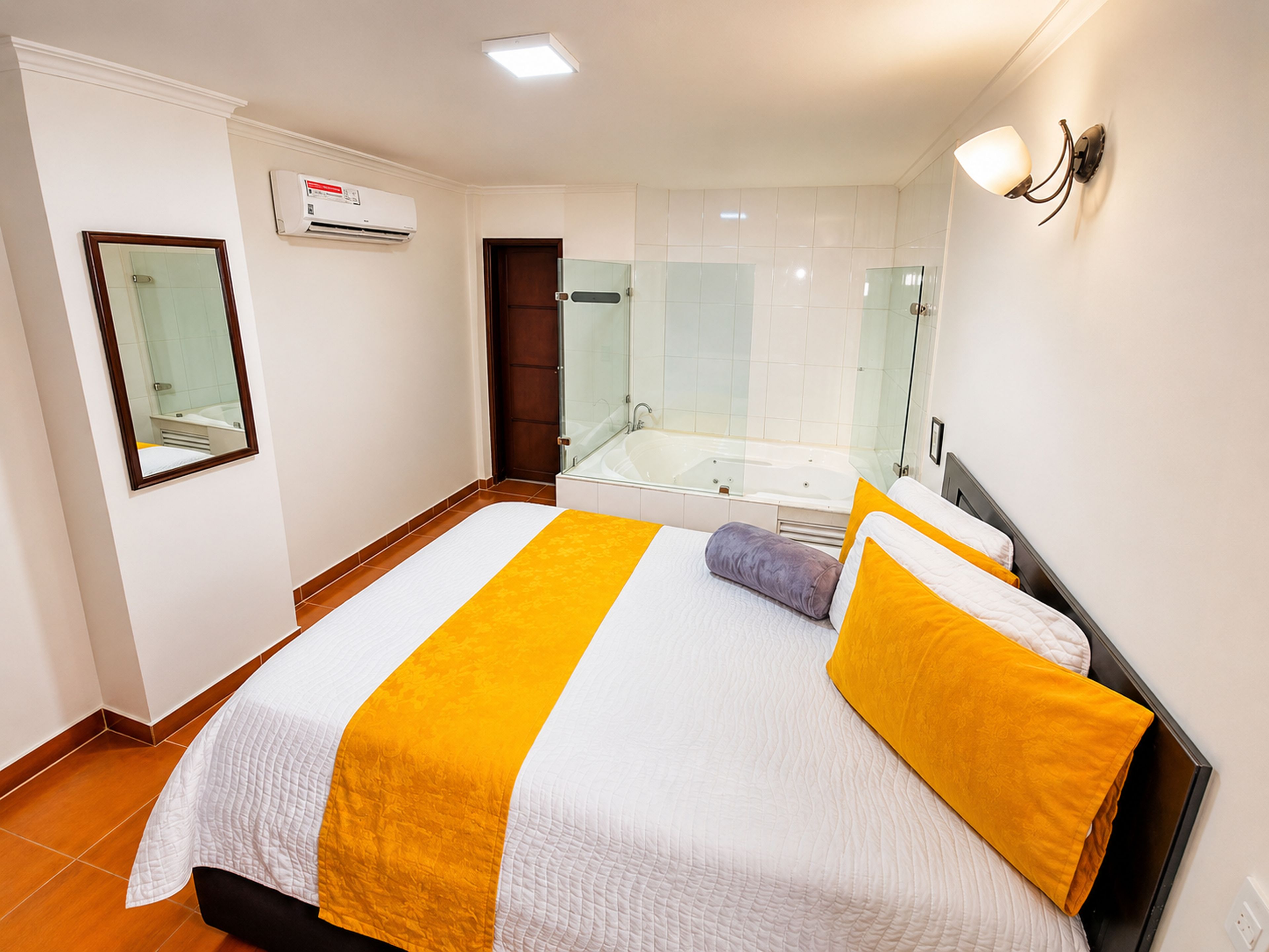 Una habitación de hotel con una cama, un baño con bañera y un espejo en la pared.