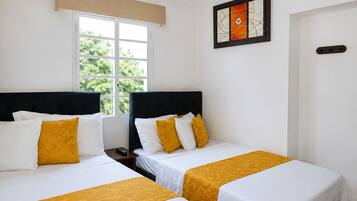 Habitación de hotel con dos camas, una ventana con vista a follaje, una obra de arte enmarcada en la pared y una puerta.