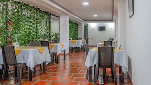 En restaurant med borde dækket af hvide duge og stole med gule bånd.