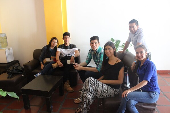 A group of people seated on a couch in a room with a water dispenser and a small table. - Hotel Avenida 3 Real (Cali)