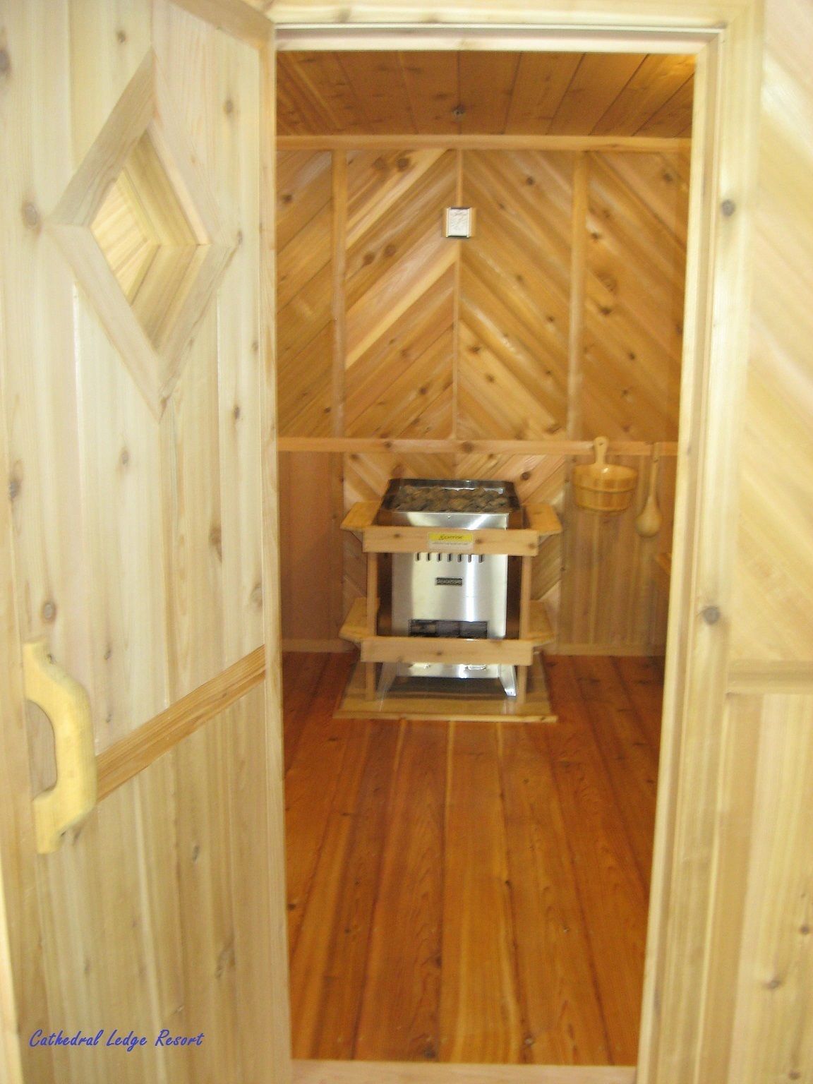 A wooden cabin with a central heating unit, a small table, and a hanging basket.