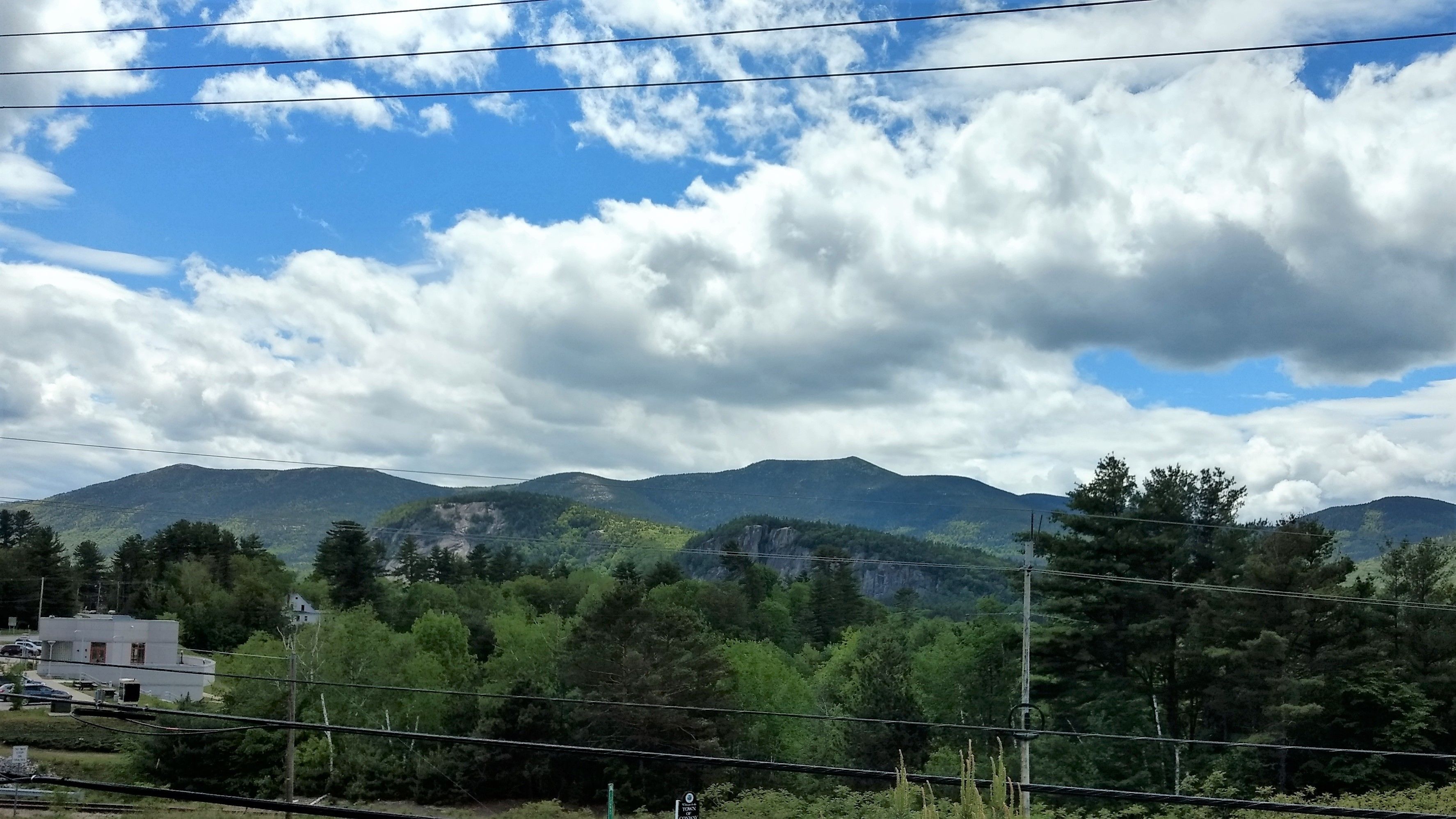 A mountainous landscape with a clear sky and power lines in the foreground.