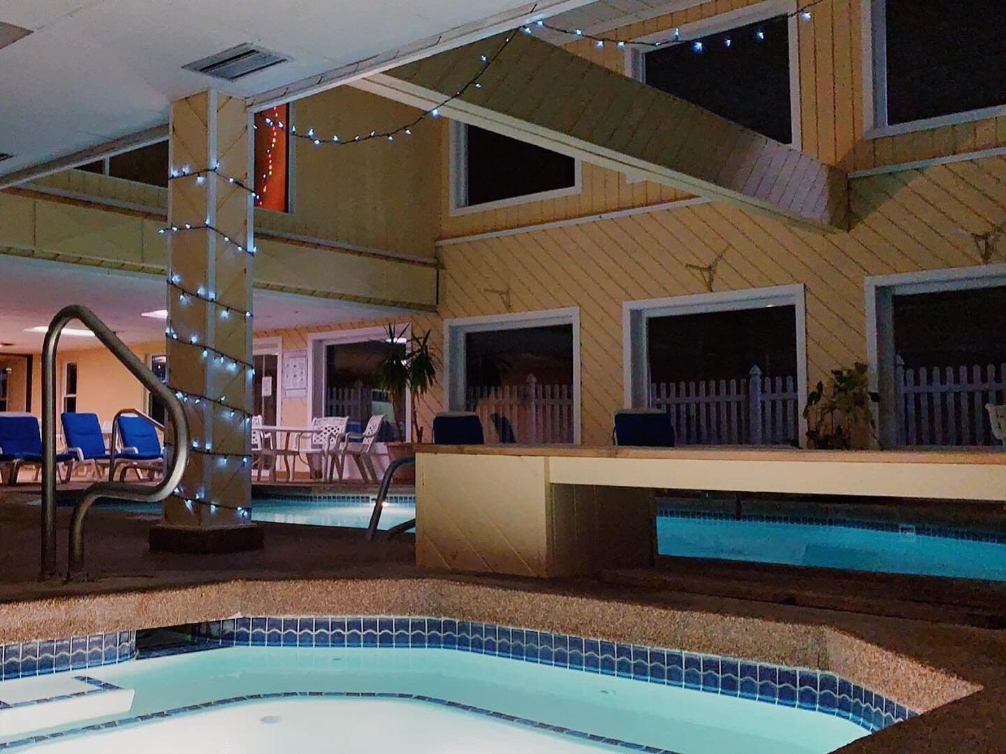 A pool area with a small pool, lounge chairs, and a staircase leading to an upper level.
