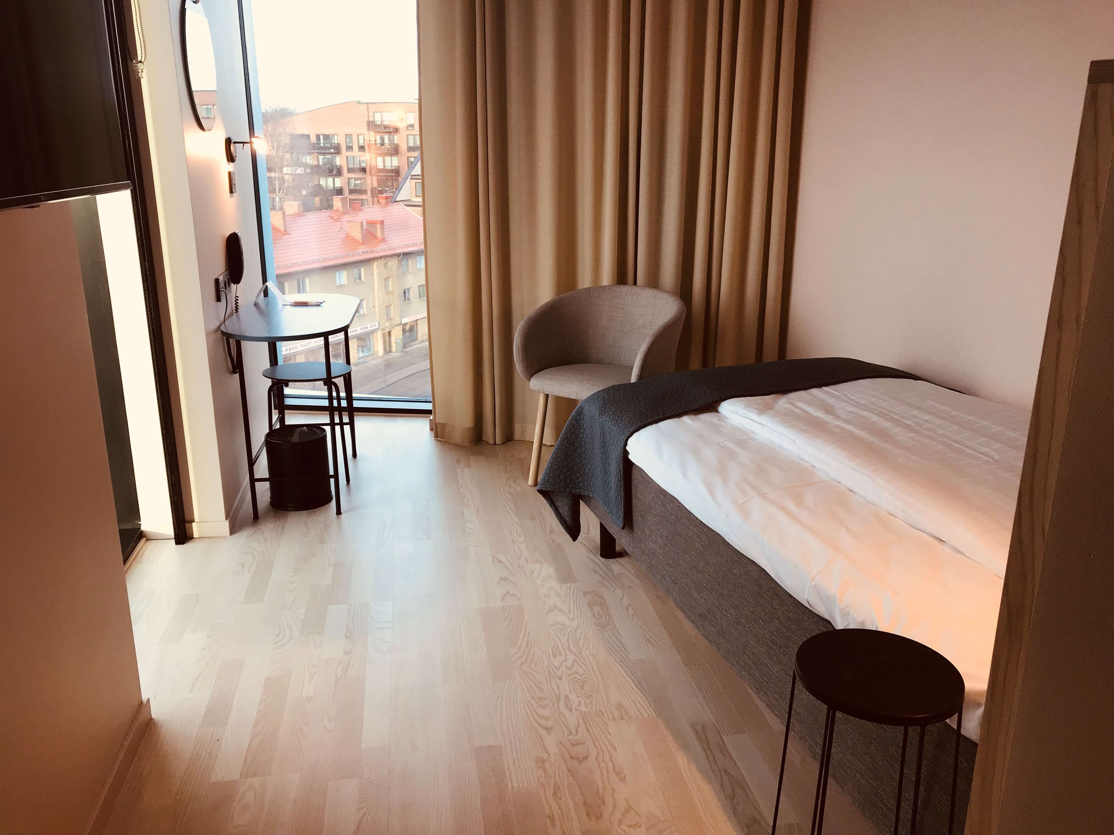 Una camera d'albergo con un letto, una sedia, un tavolino e vista sulla città.