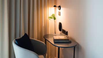 Ett modernt rum med en stol, ett litet bord med en lampa, en växt och en bok.