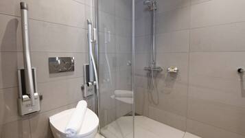 Un baño moderno con ducha envuelta en vidrio, inodoro y secador de manos.