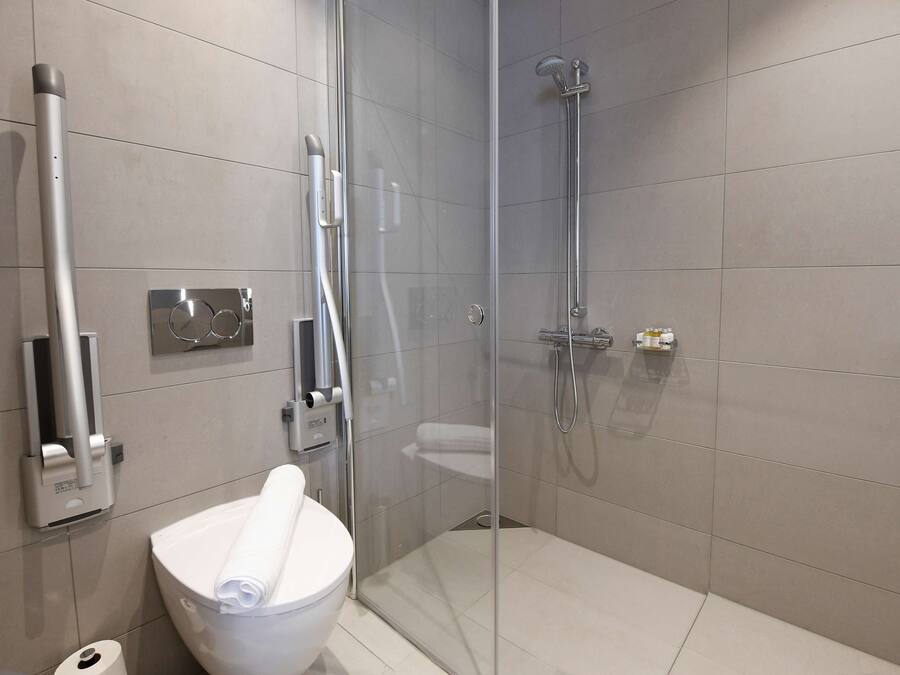 Un baño moderno con ducha envuelta en vidrio, inodoro y secador de manos.