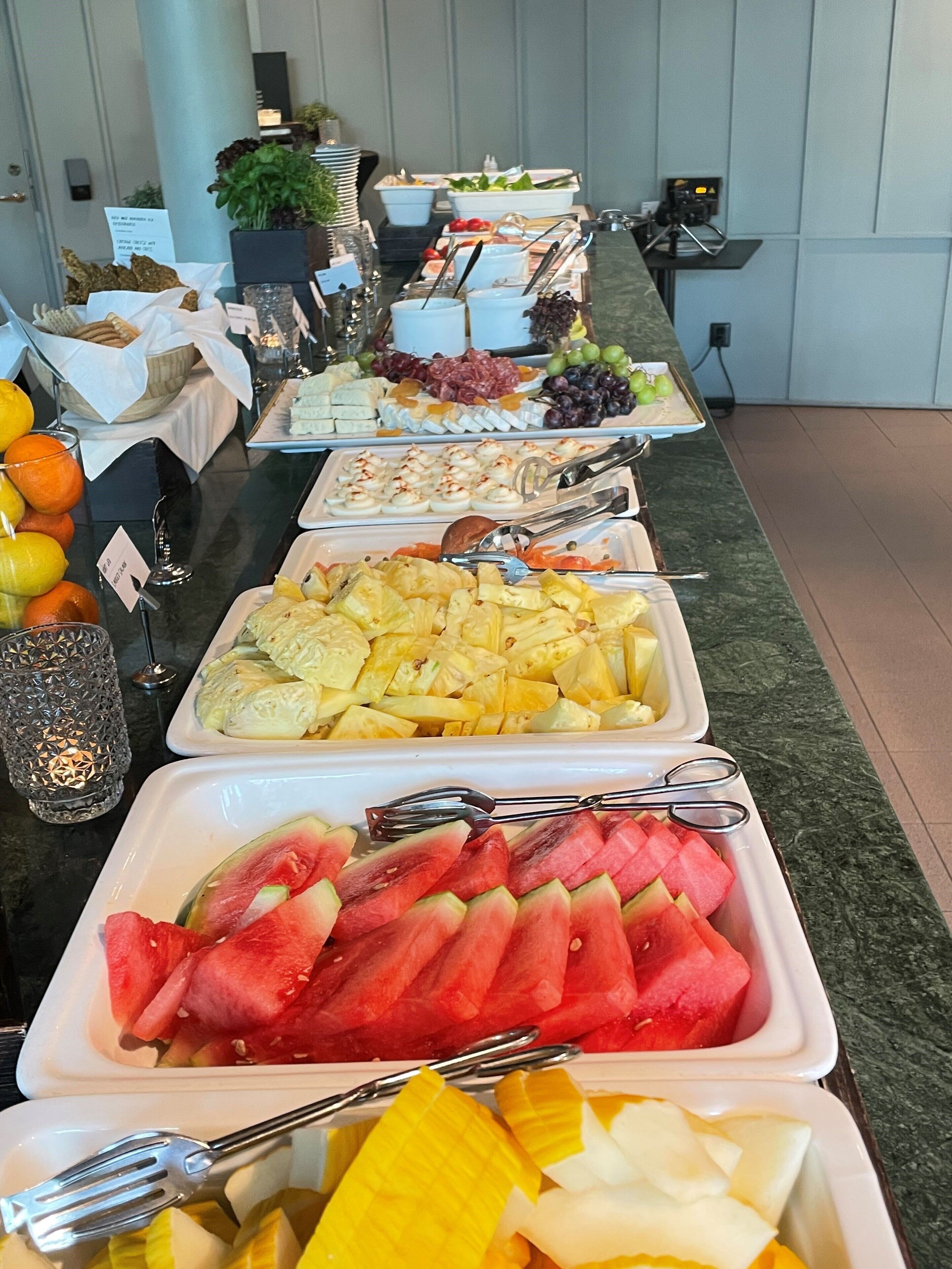 A buffet with various food items including fruits, cheeses, and meats.