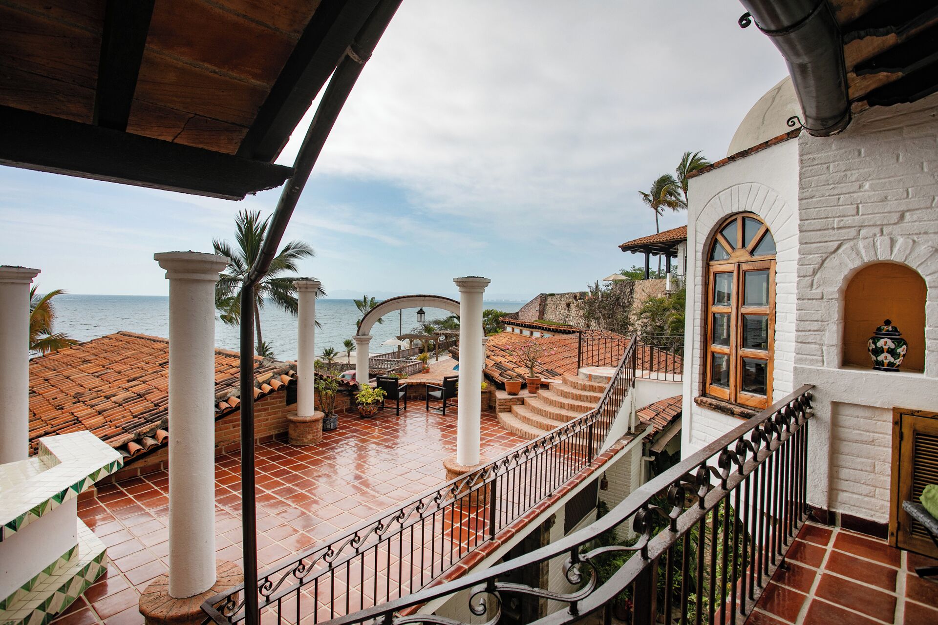 A coastal property with a terrace, white columns, and a view of the sea.