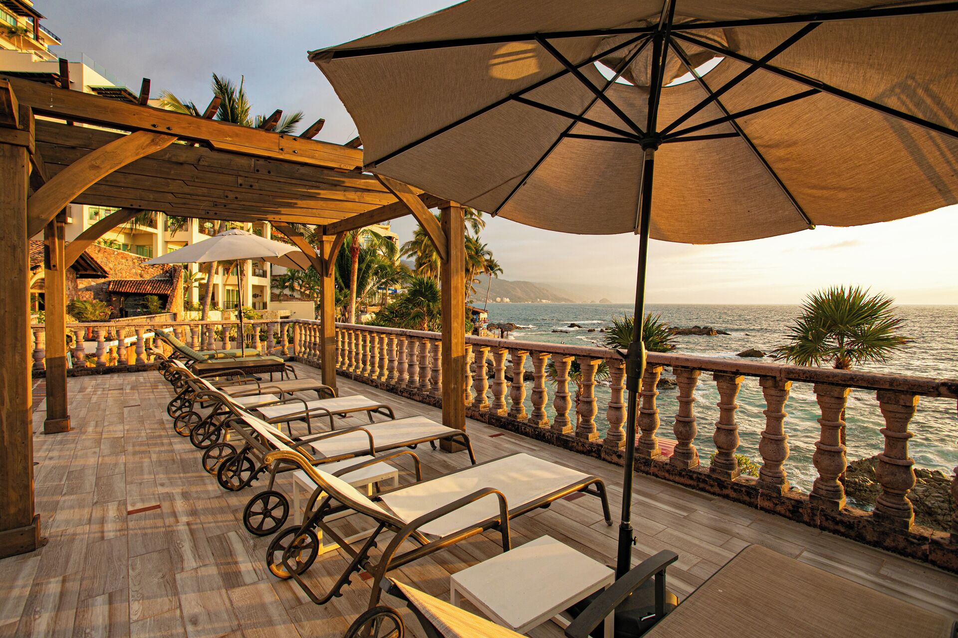 A wooden deck with sun loungers and umbrellas overlooking the ocean.