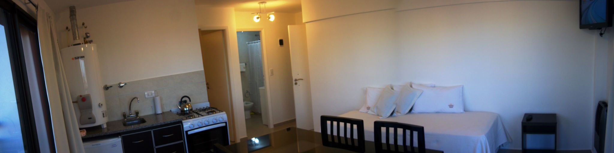 Camera d'albergo con un letto, una scrivania con un bollitore, un lavandino e uno specchio.