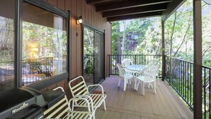 Une terrasse extérieure couverte, équipée d’un barbecue, de chaises blanches et d’une table.