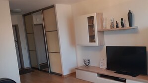 Una sala de estar moderna con un sofá, una mesa de centro, un televisor y un mueble con objetos decorativos.