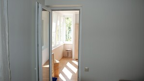 Un pasillo estrecho con una puerta que da a una habitación con ventana.