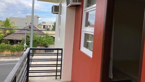 A balcony with a metal railing, an air conditioning unit, and a window. - Golite Hostel (Legazpi)